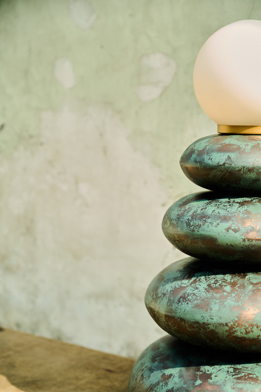 Decorative lamp with a textured green base and white bulb against a neutral background