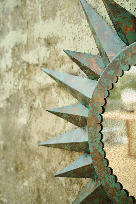 Rustic metal sunburst sculpture against a textured wall