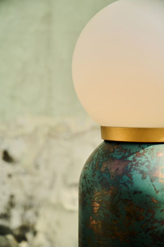 Close-up of a textured green bottle with a white cap on a blurred natural background