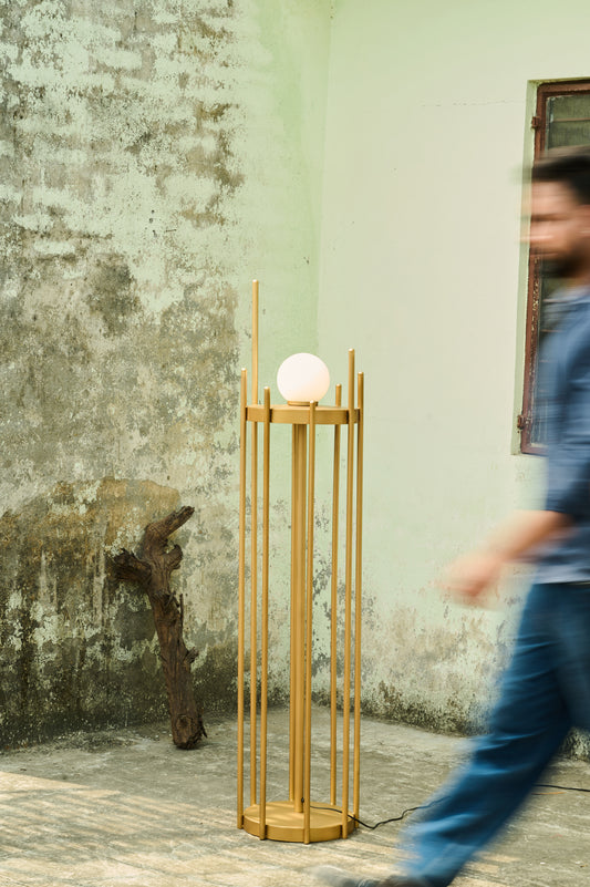 Wooden lamp with a spherical light bulb against a textured wall.