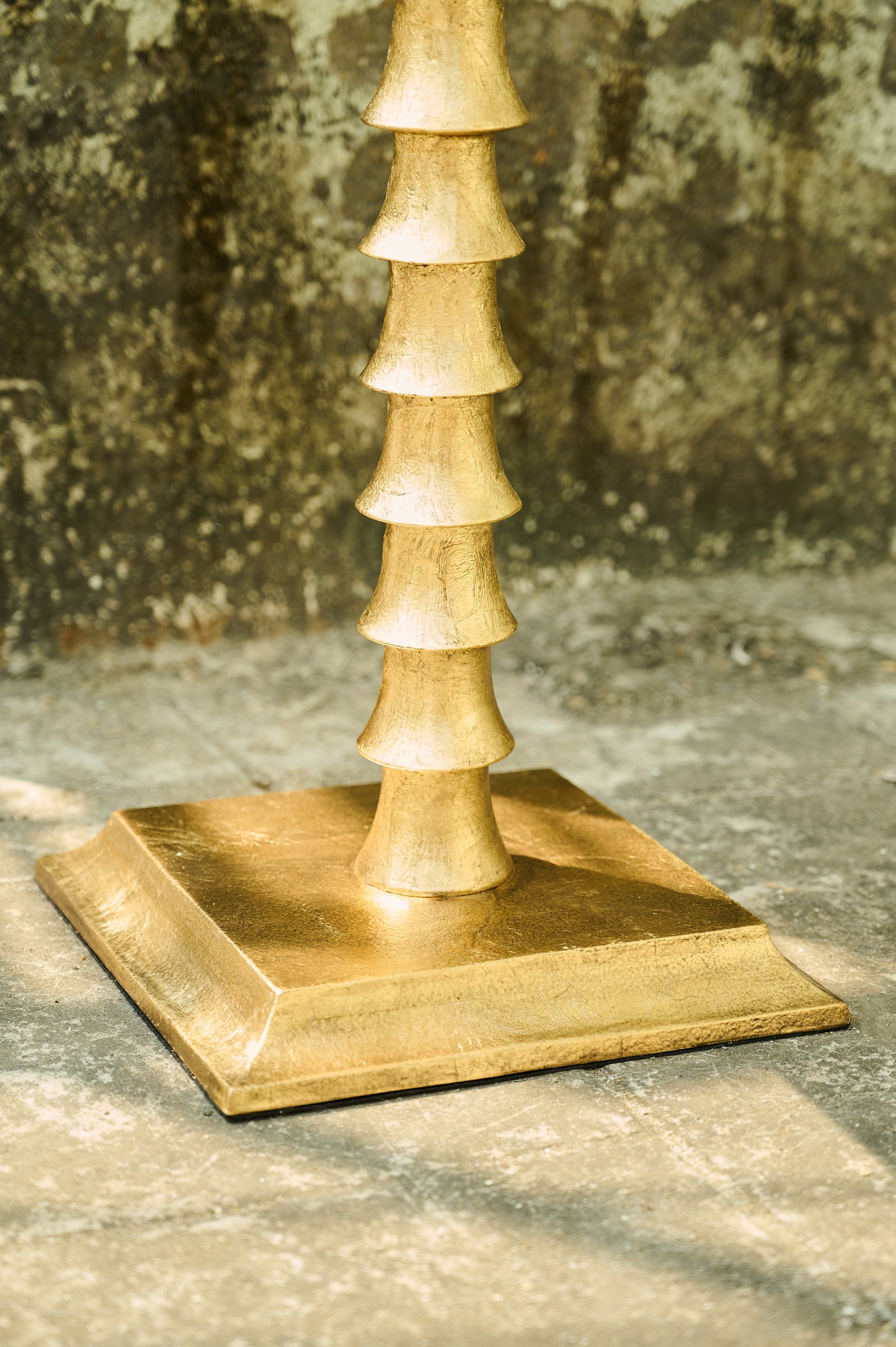 Gold decorative object with a square base on a textured surface
