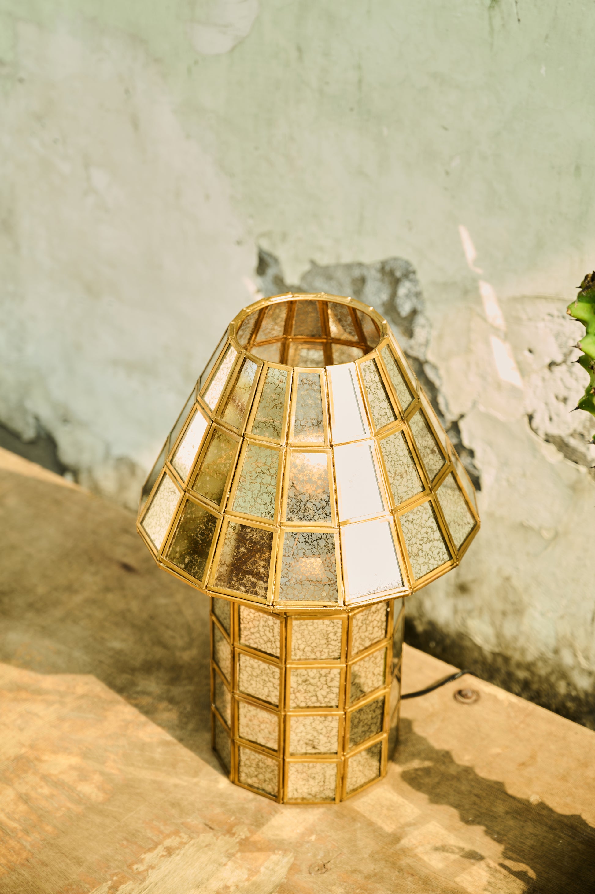 Gold geometric lamp on a wooden surface with a textured wall background