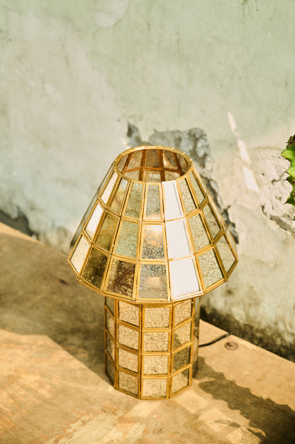 Gold geometric lamp on a wooden surface with a textured wall background