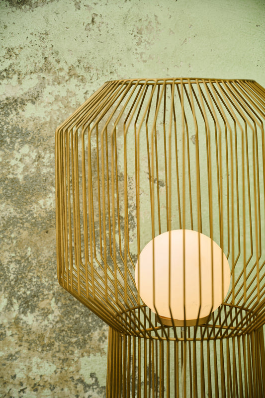 Woven lamp with a warm glow against a textured wall.