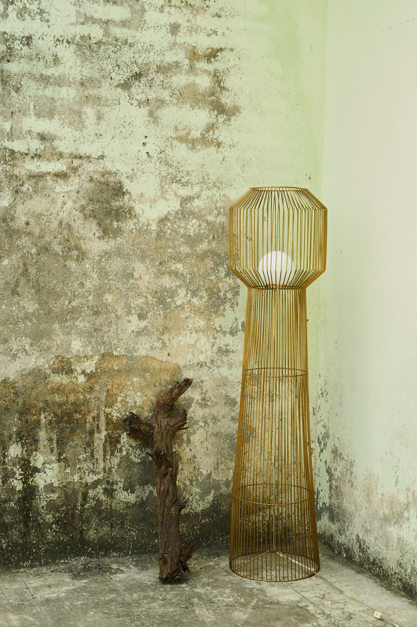 Tall woven floor lamp against a textured wall