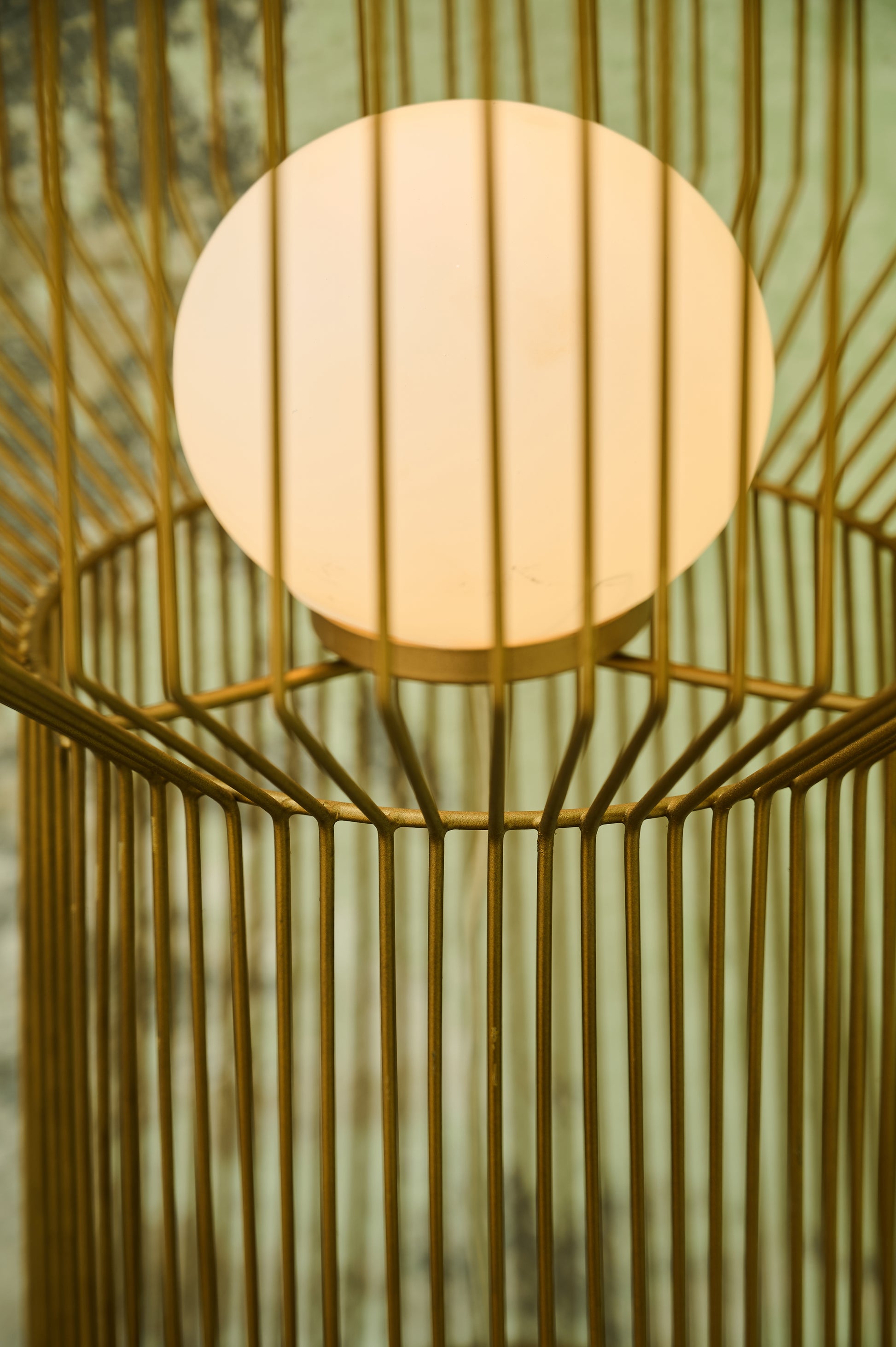 Decorative lamp with a gold cage design and soft light inside.