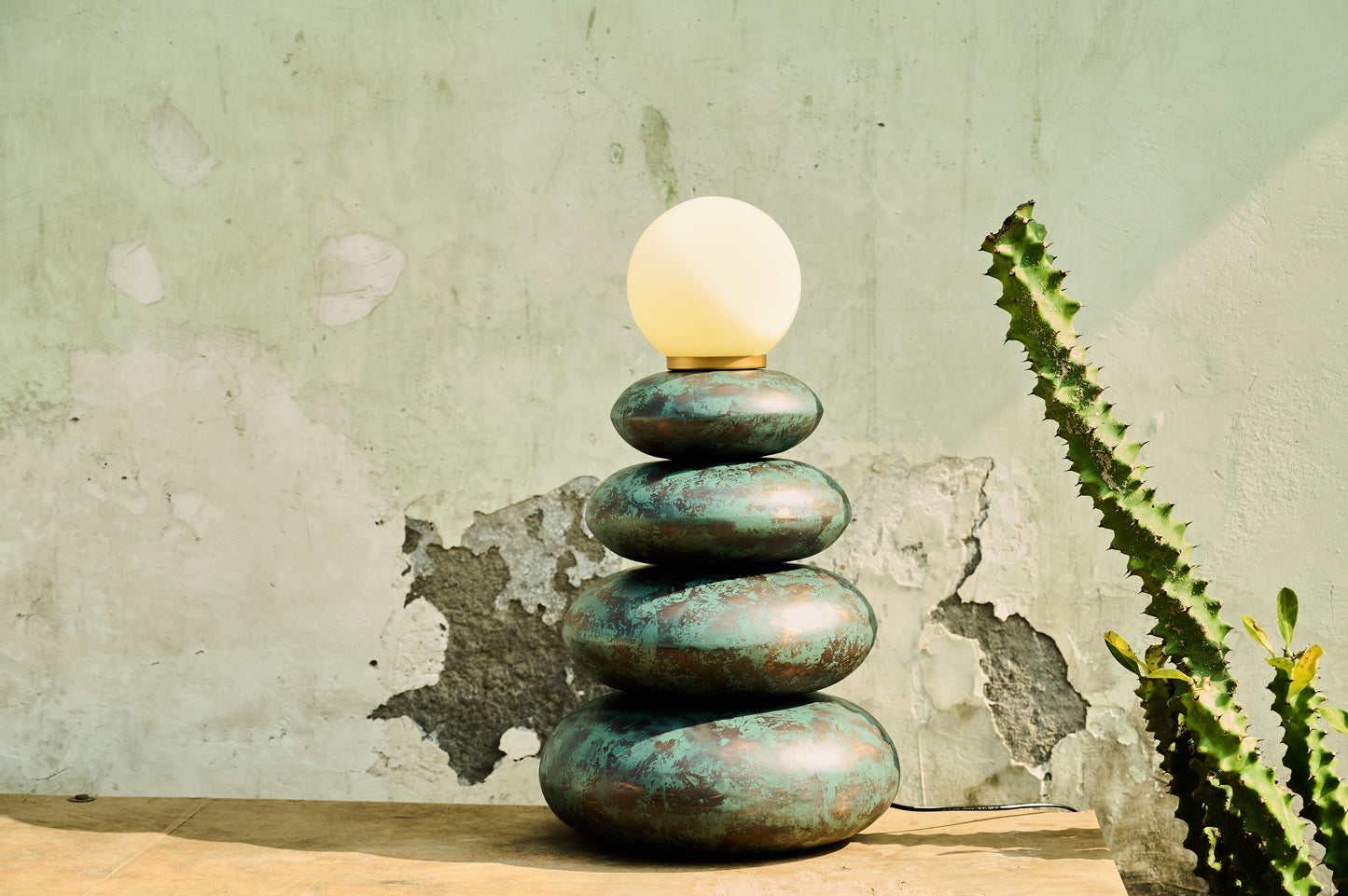 Stack of stones with a light bulb on top against a textured wall