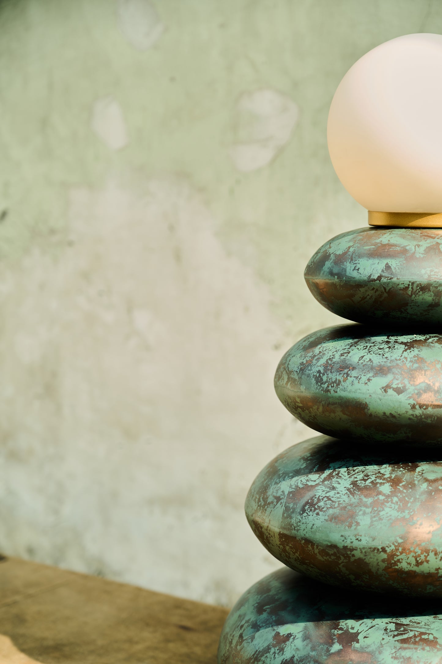 Decorative lamp with a textured green base and white bulb against a neutral background
