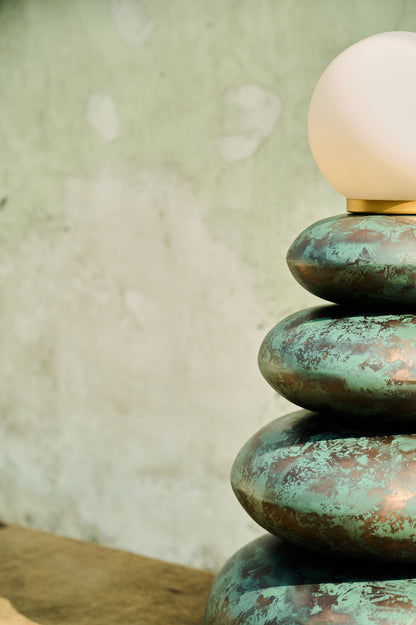 Decorative lamp with a textured green base and white bulb against a neutral background