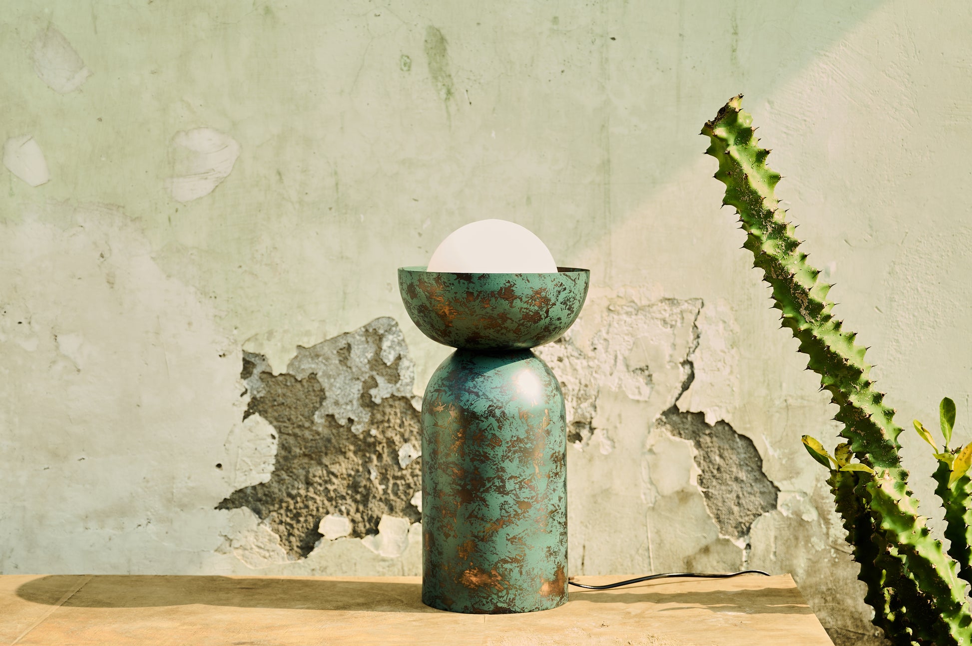 Decorative lamp with a textured surface on a wooden surface against a rustic wall.