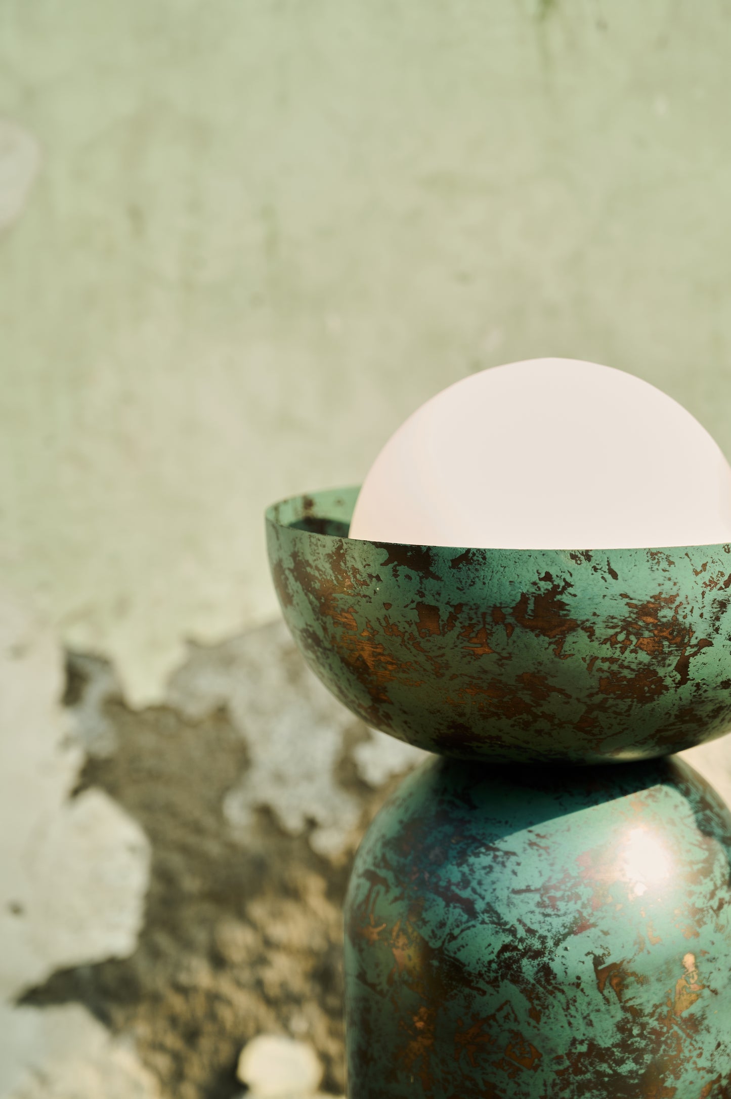 Green ceramic bowl with a white sphere on a textured green background