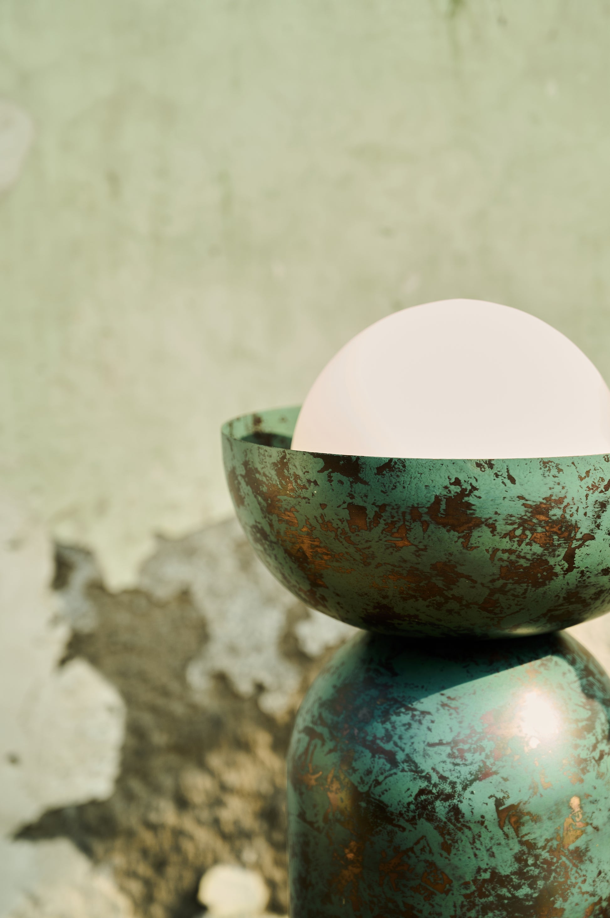 Green ceramic bowl with a white sphere on a textured green background