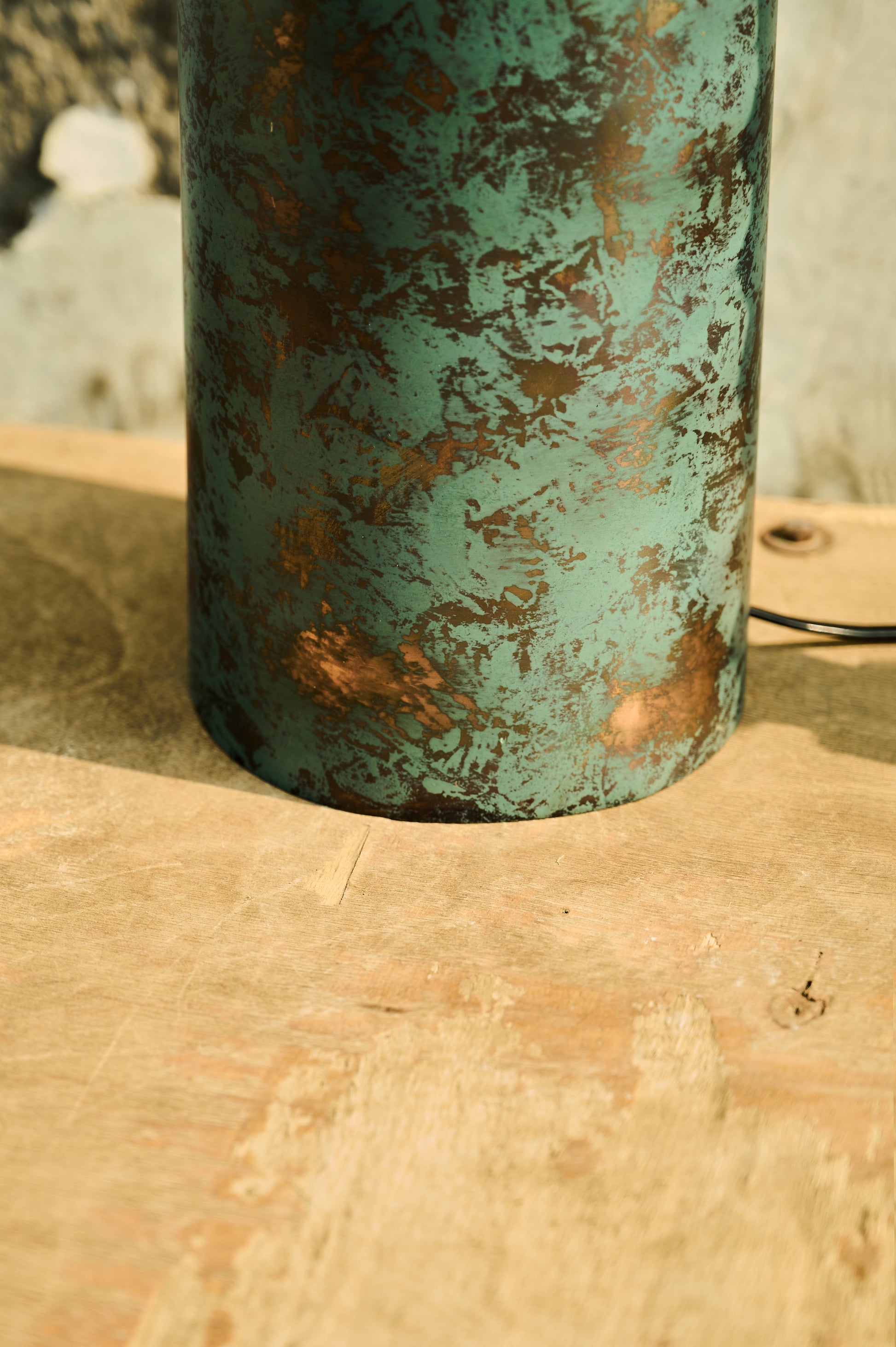 Rustic metal vase with a textured surface on a wooden surface