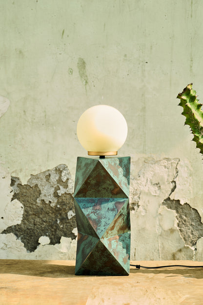 Table lamp with geometric base against a textured wall