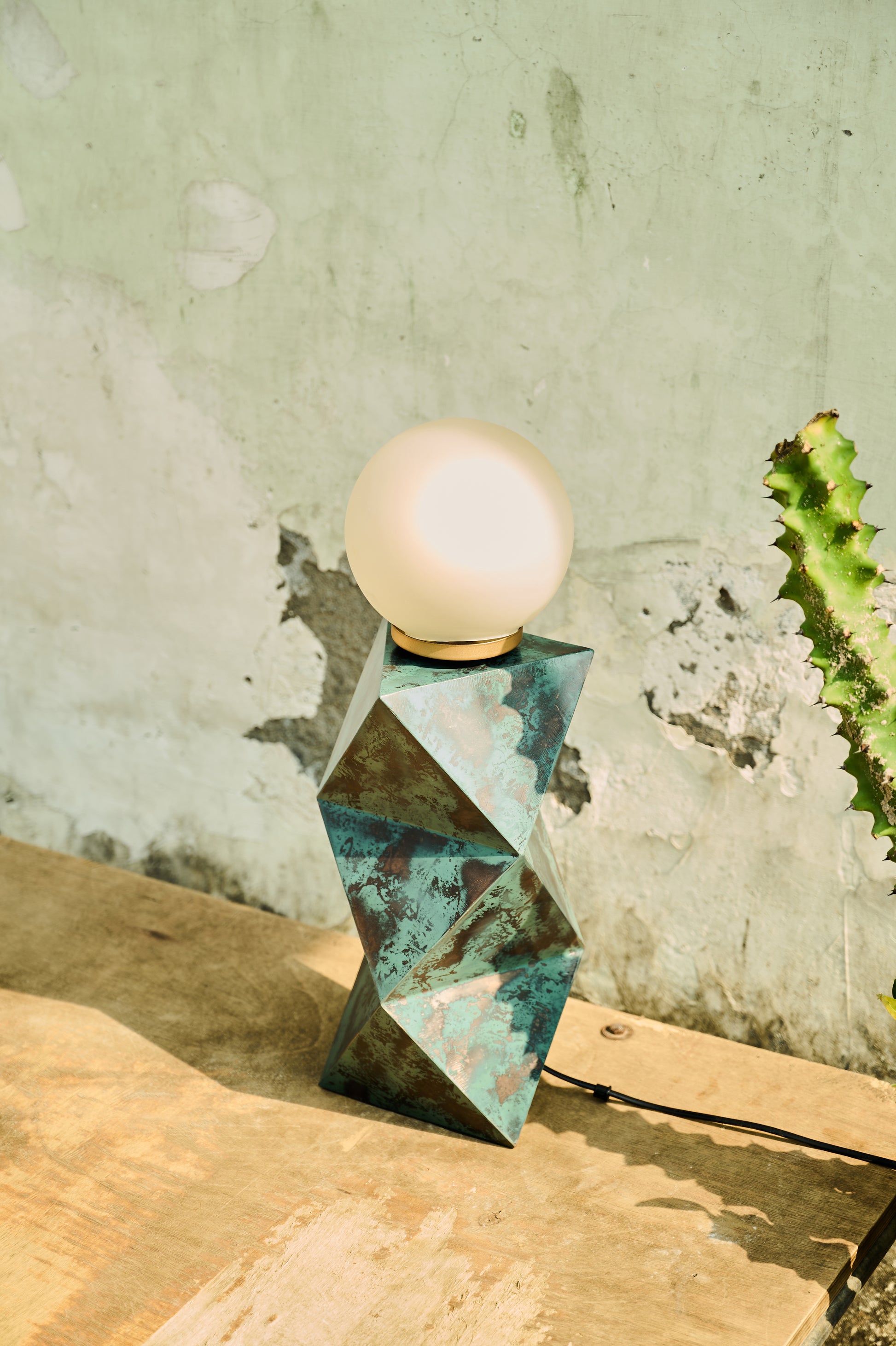 Geometric metal lamp with a round bulb on a textured surface and wall background
