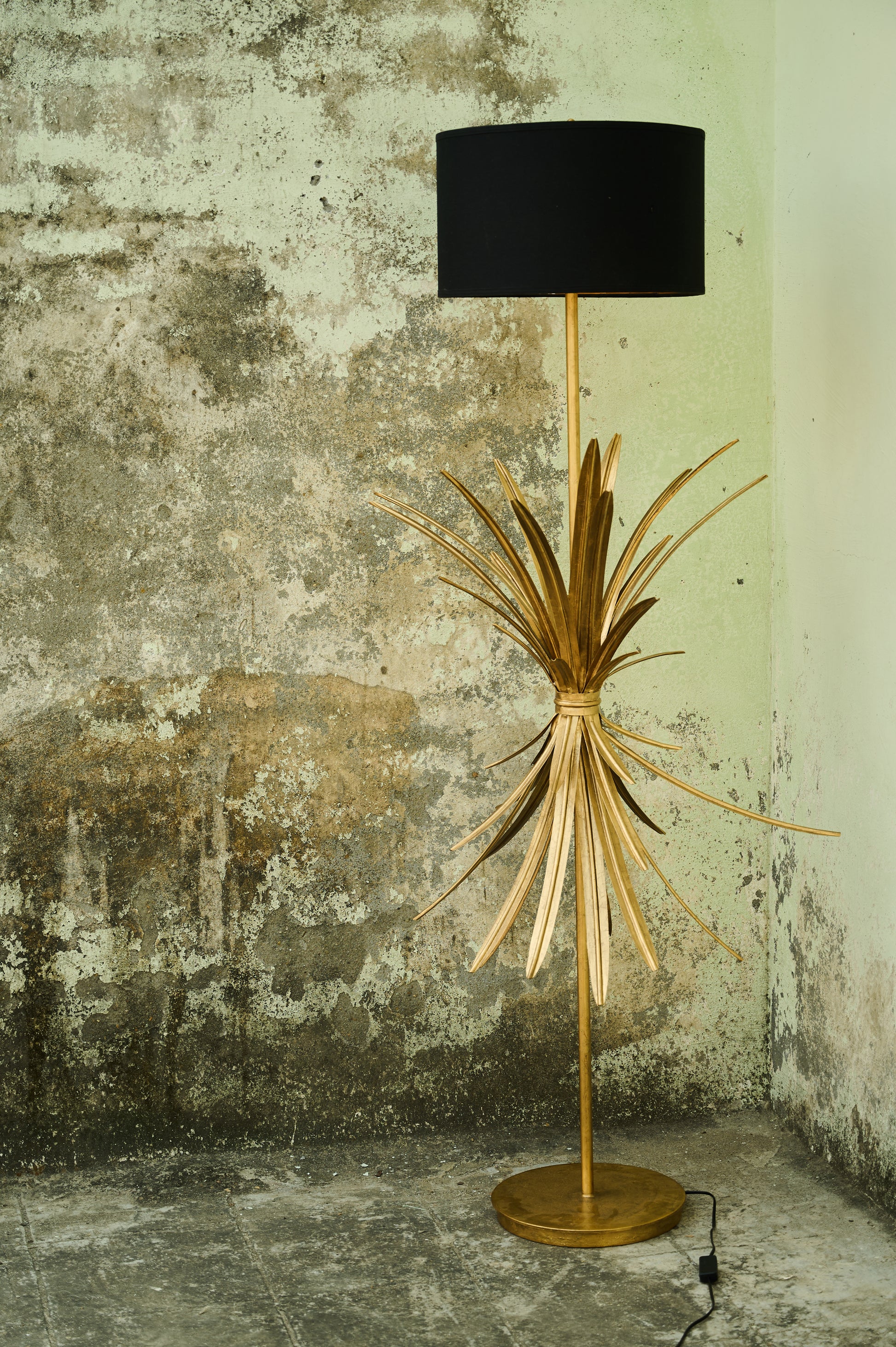 Floor lamp with a unique design against a textured wall.