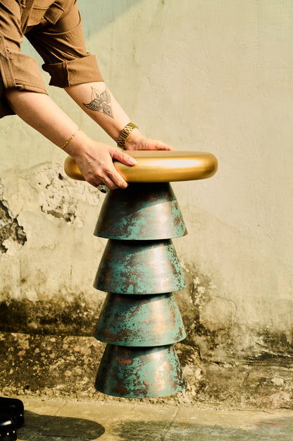 Person interacting with a unique, layered stool against a textured wall.