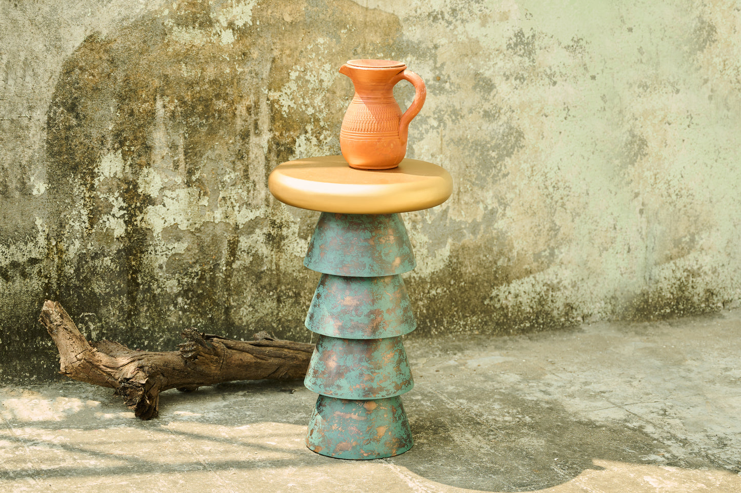 Stacked ceramic pieces with a terracotta vase on a textured stone surface