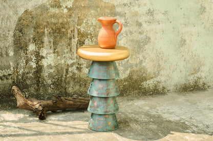 Stacked ceramic pieces with a terracotta vase on a textured stone surface