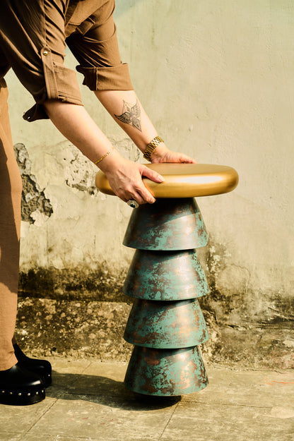 Person interacting with a unique, tiered stool against a textured wall.