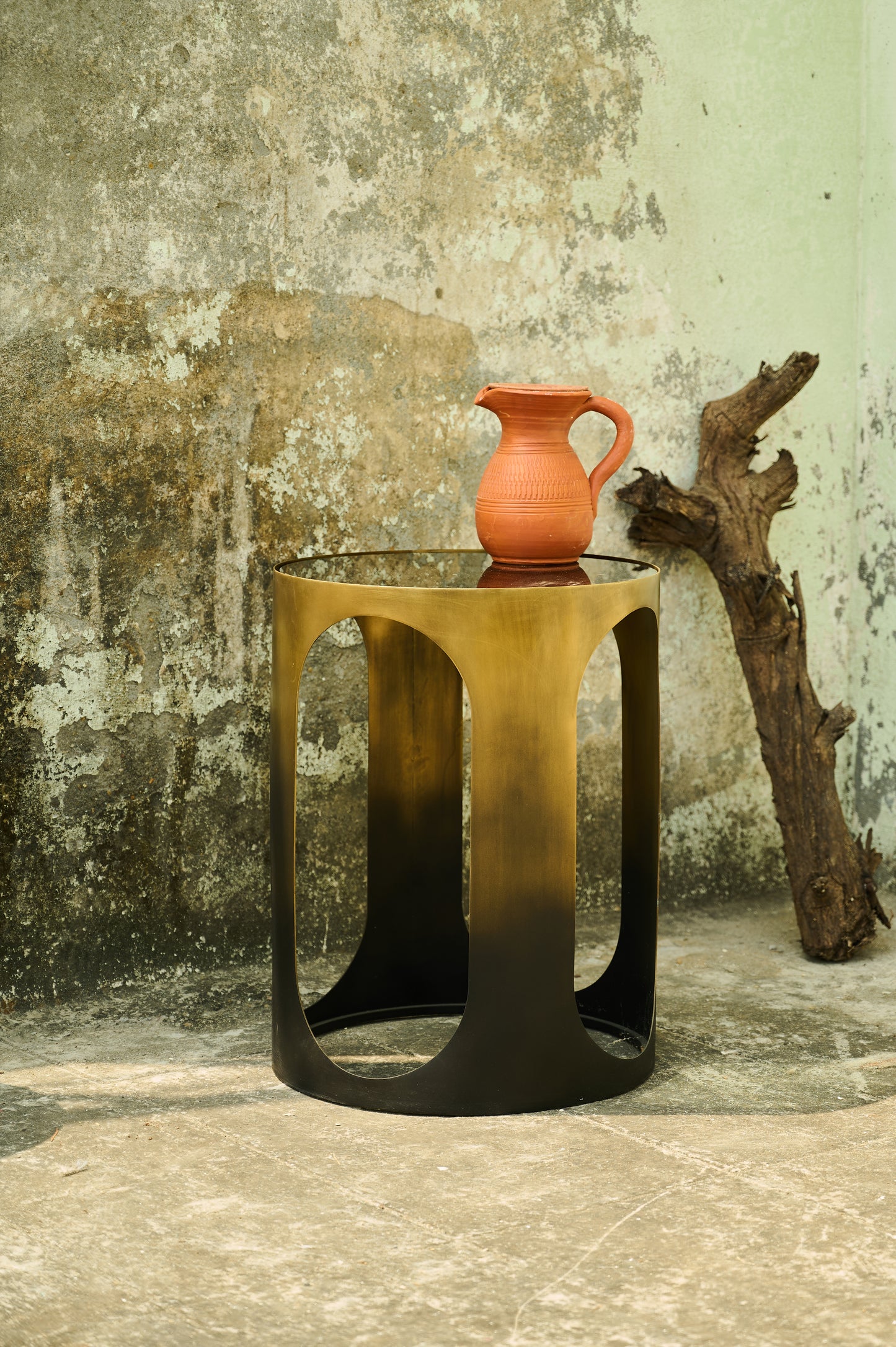 Small table with a terracotta vase against a textured wall.