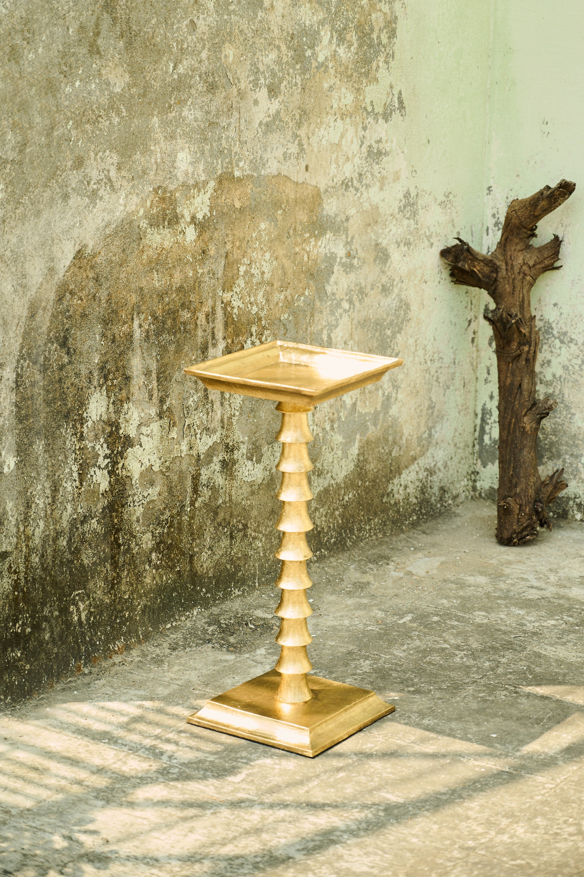 Decorative gold pedestal against a textured wall