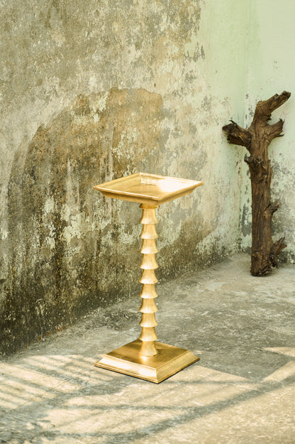 Decorative gold pedestal against a textured wall