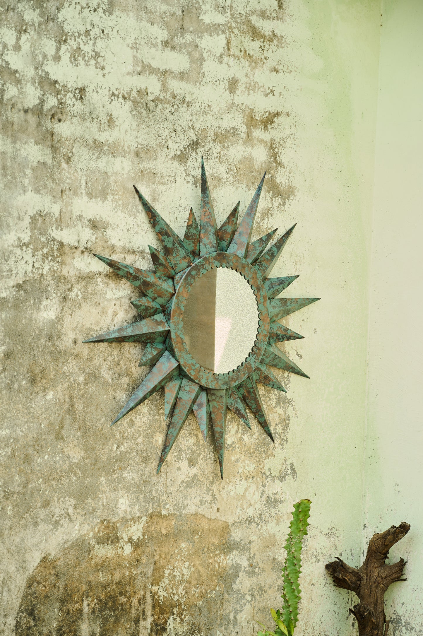 Decorative sun-shaped mirror on a textured wall
