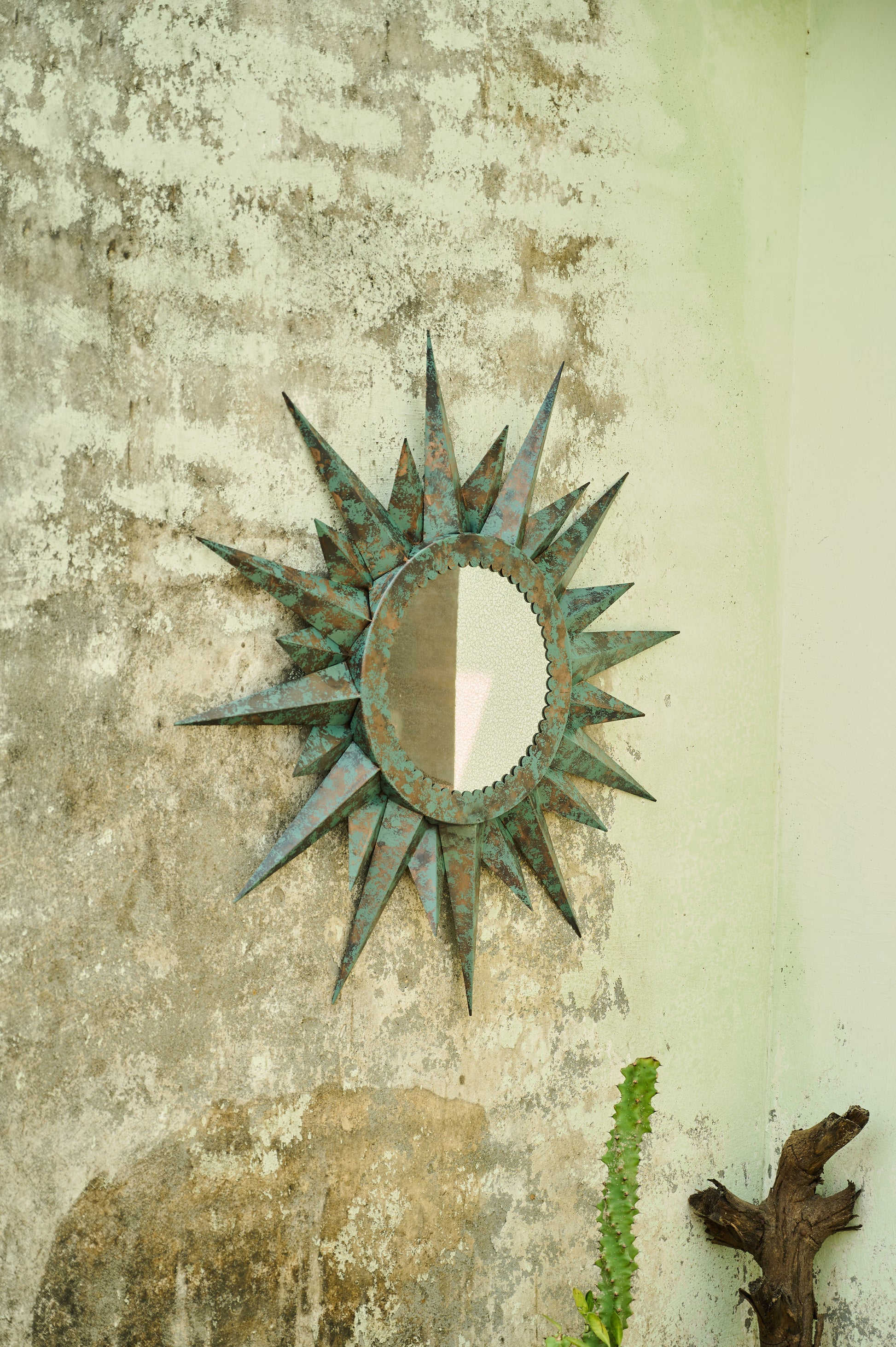 Decorative sun-shaped mirror on a textured wall