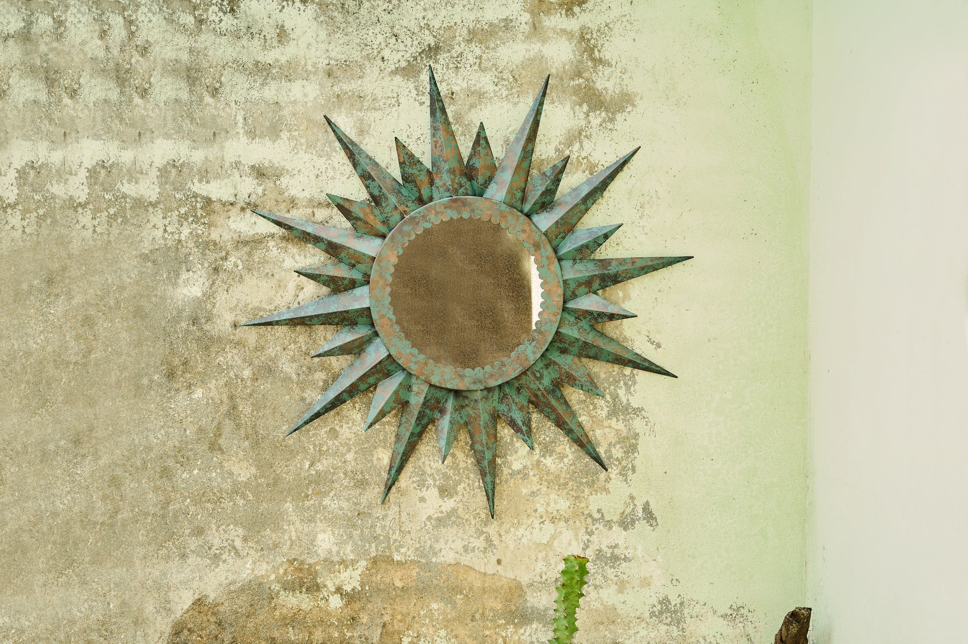 Decorative sun-shaped mirror on a textured wall