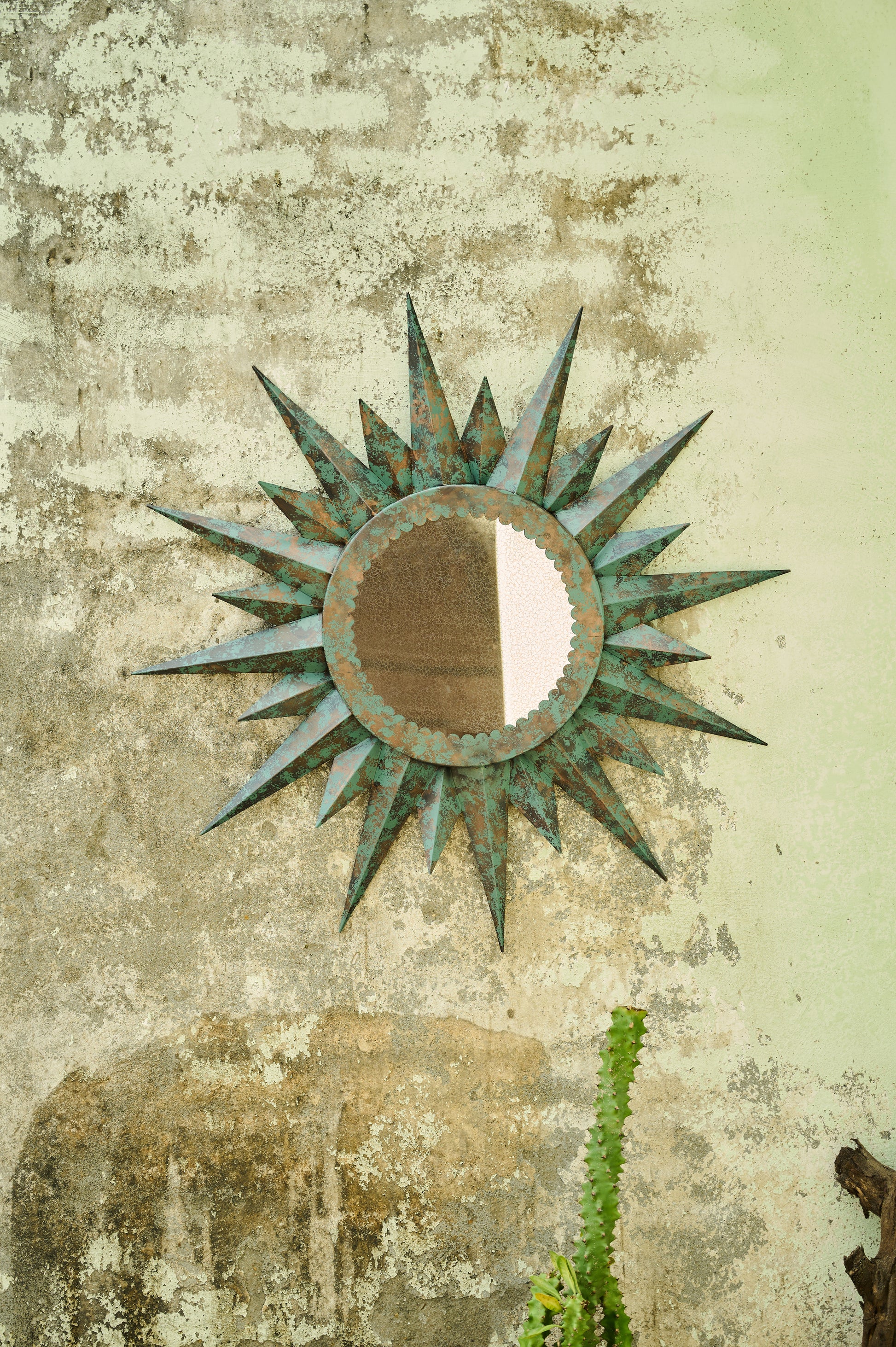 Decorative sun-shaped mirror on a textured wall