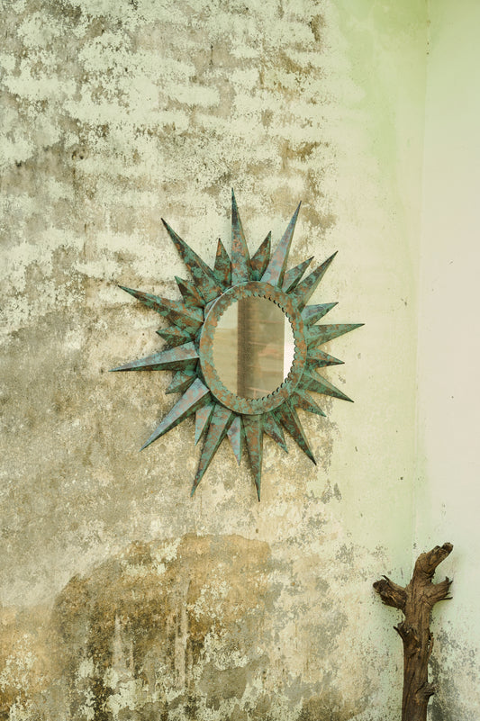 Decorative sun-shaped mirror on a textured wall