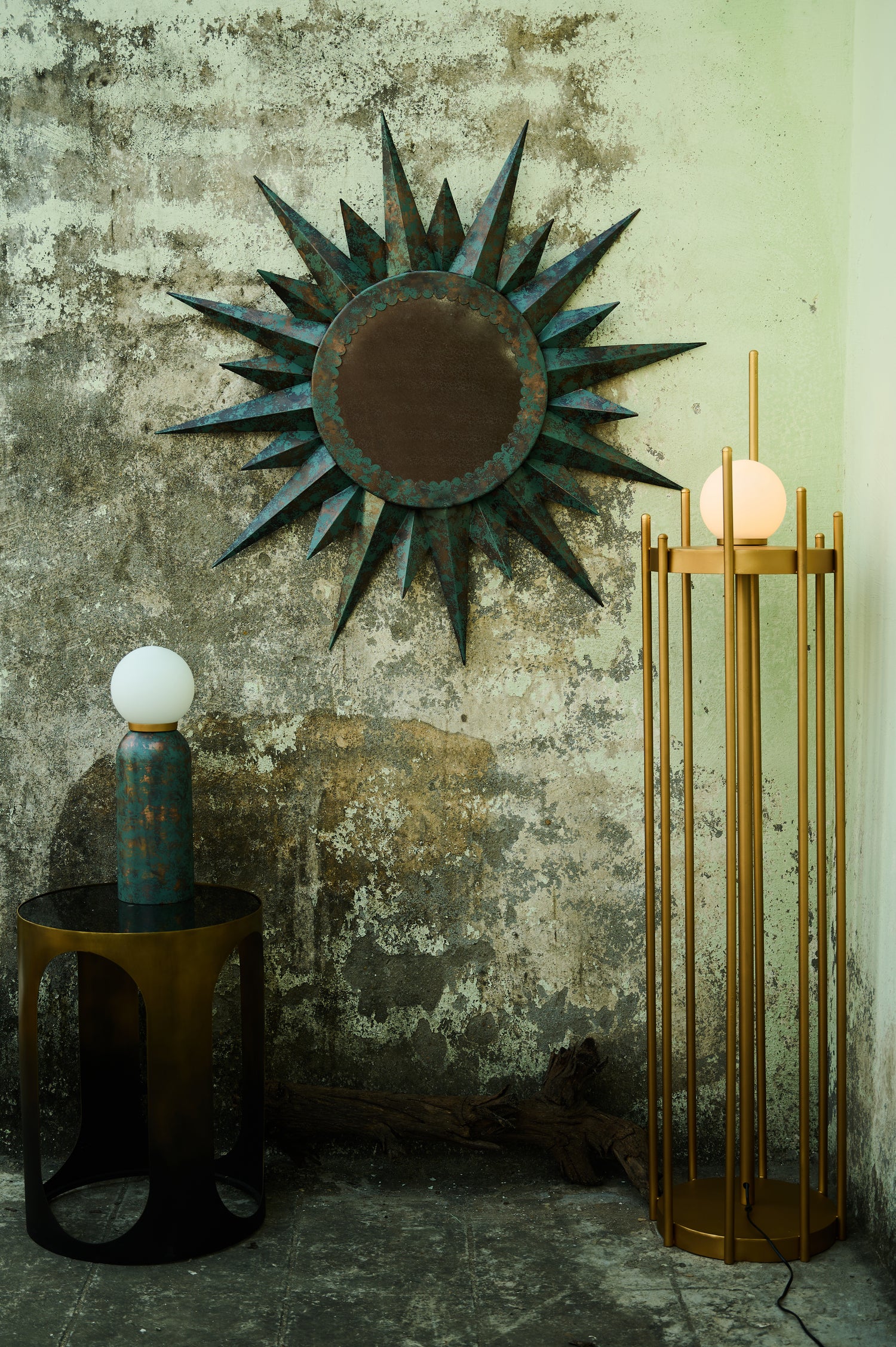Decorative sun-shaped mirror on a textured wall with a lamp and small table.