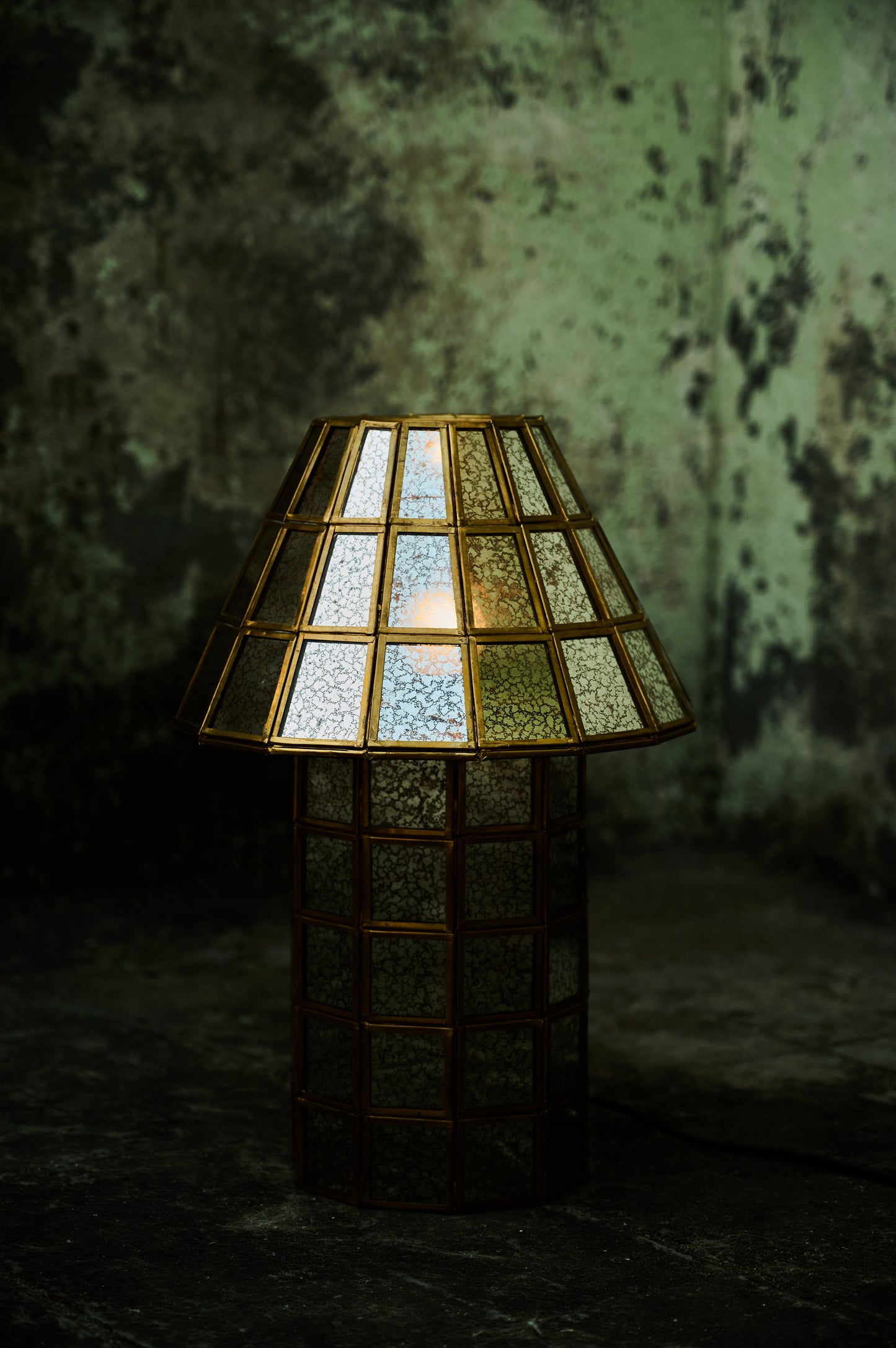 Decorative lamp with stained glass shade against a textured wall.