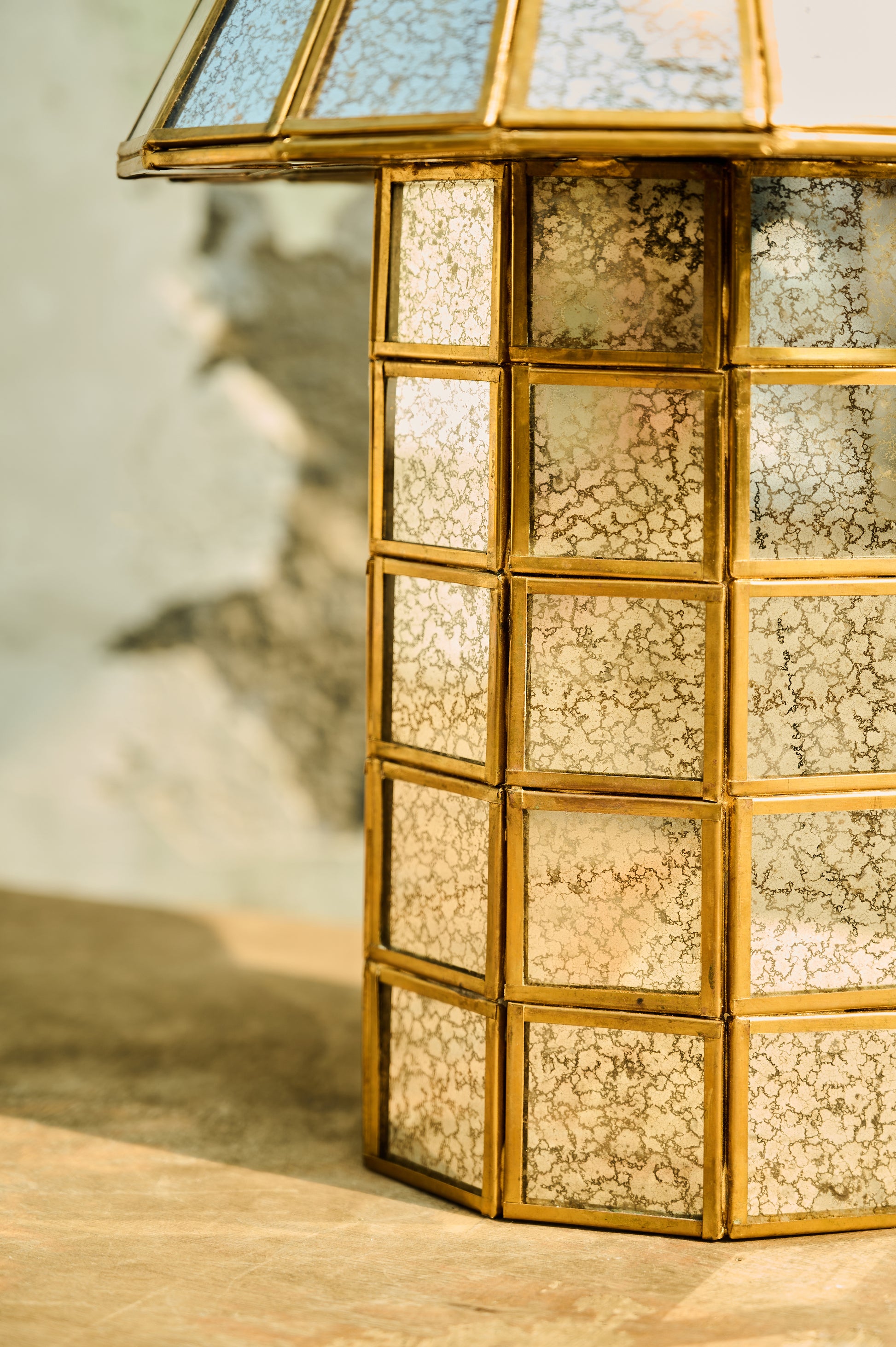 Decorative lantern with gold frame and textured glass panels on a wooden surface.