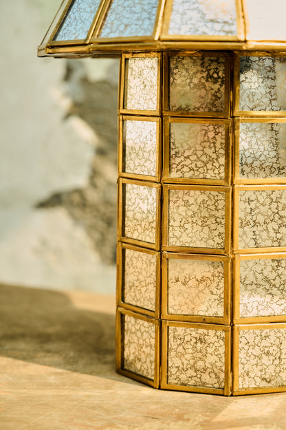 Decorative lantern with gold frame and textured glass panels on a wooden surface.