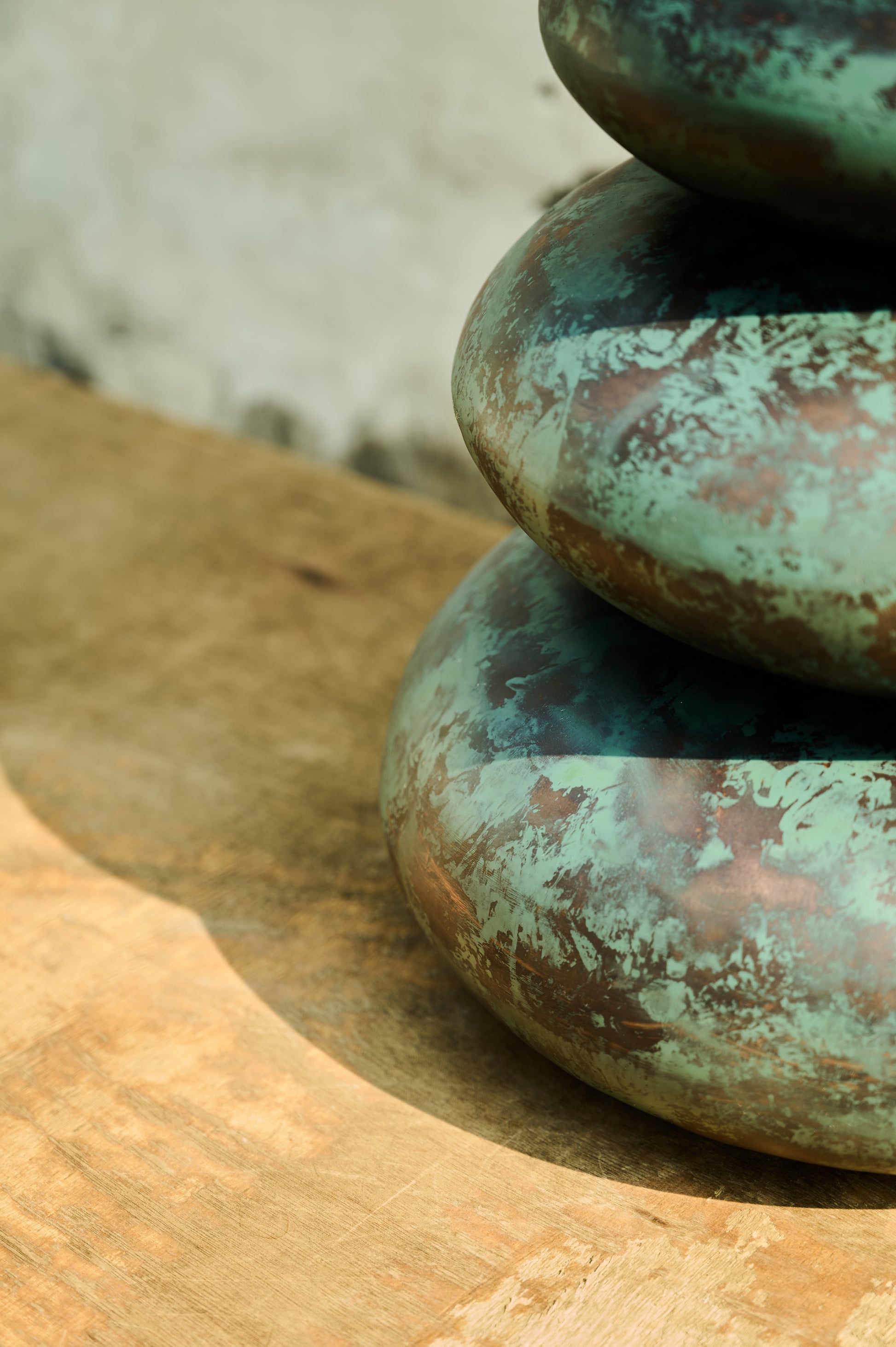 Stack of greenish-brown stones on a wooden surface with a blurred natural background