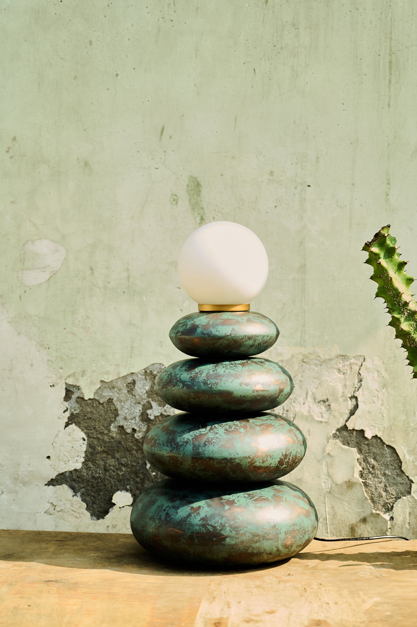 Decorative lamp with stacked stone-like bases against a textured wall.
