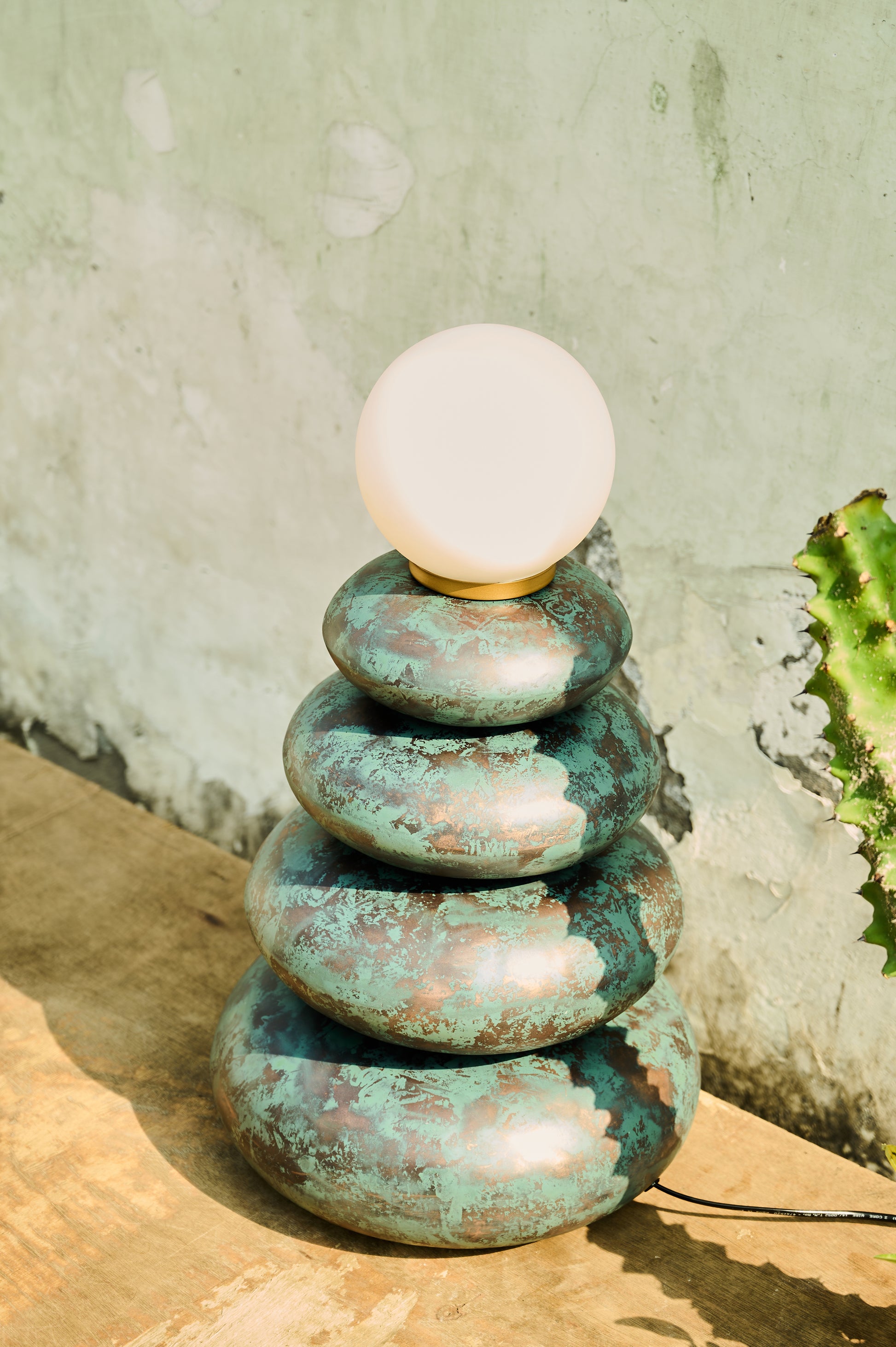 Decorative lamp with stacked stone-like bases on a textured surface