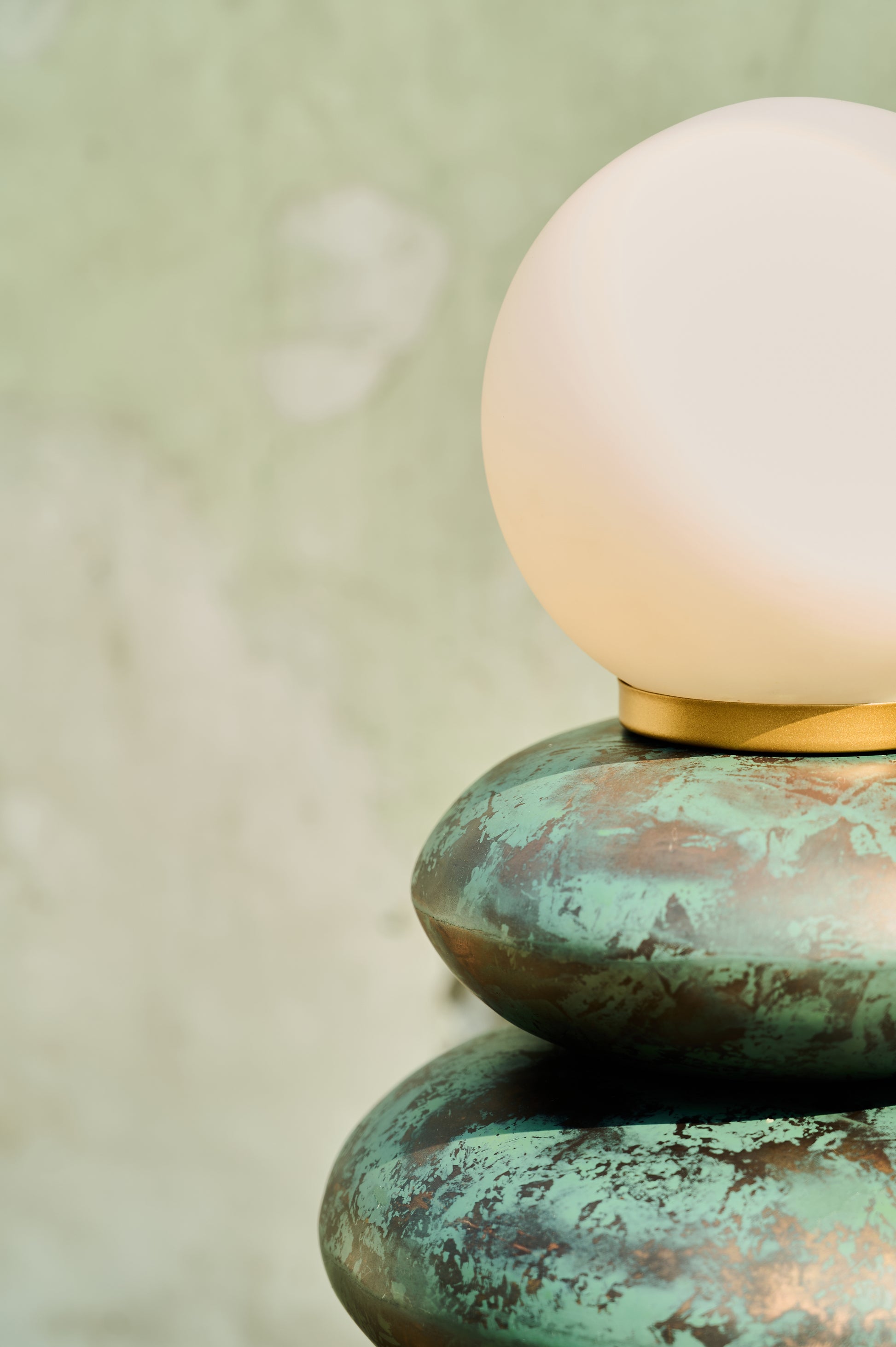 Lamp with a white shade on a textured green base against a blurred background