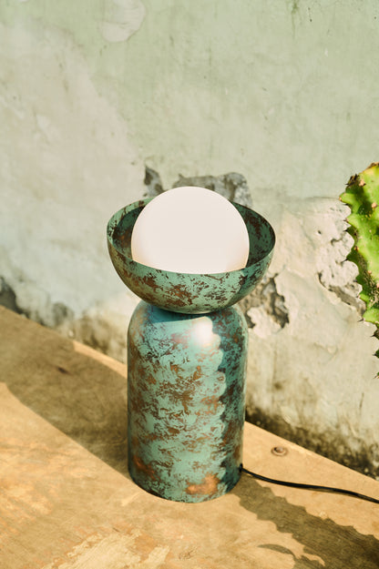Turquoise ceramic lamp with a white bulb on a stone surface