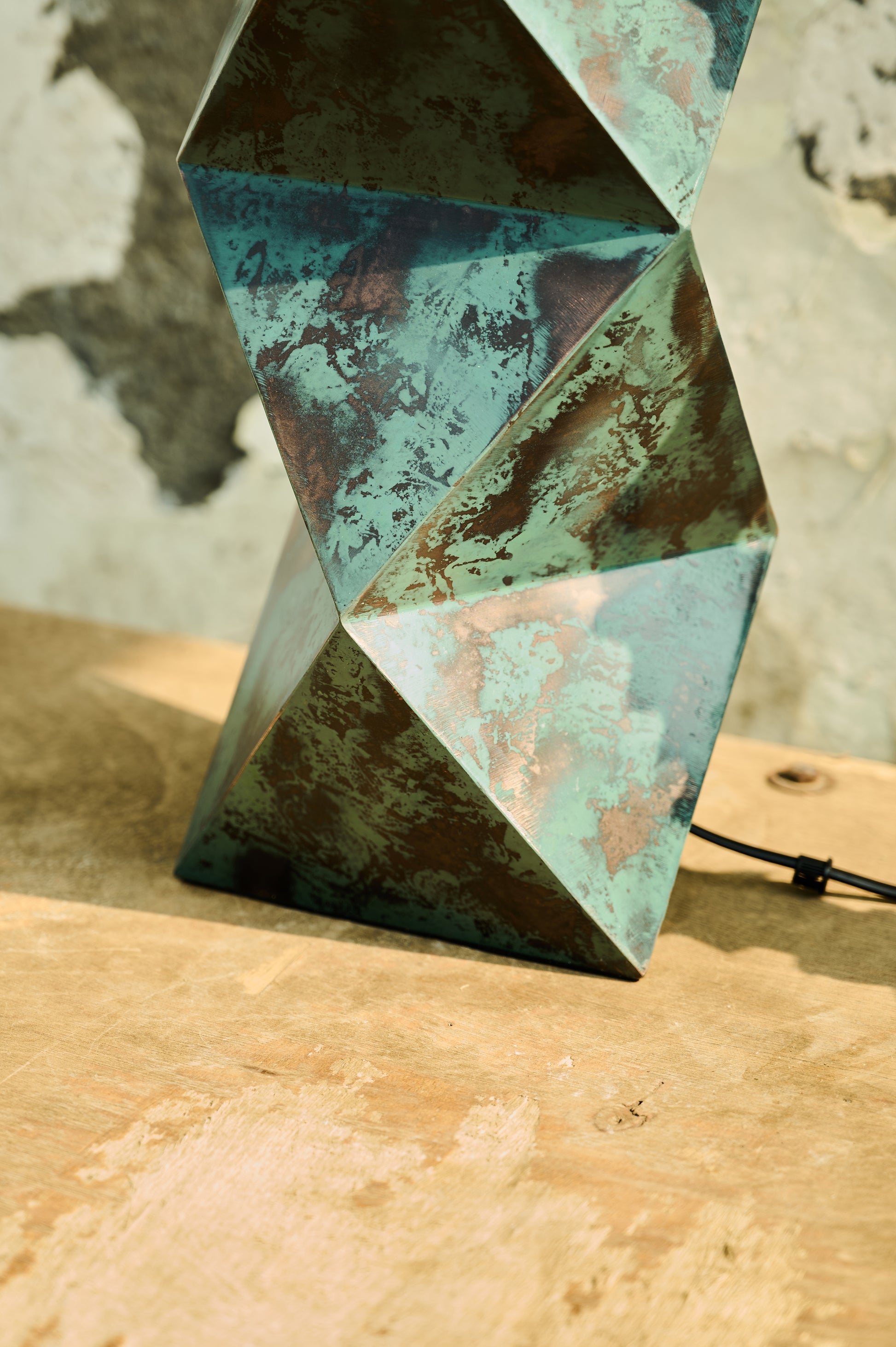 Geometric metal sculpture with a textured surface on a wooden surface