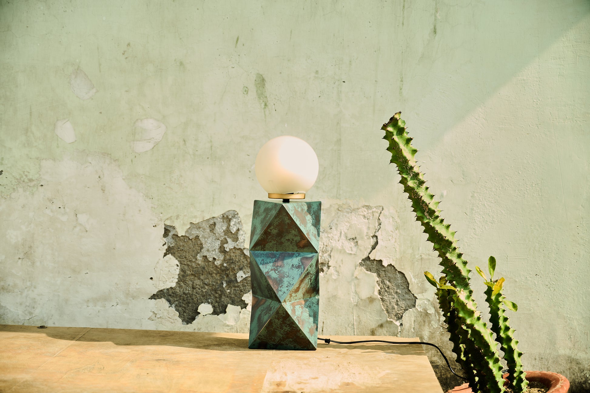 Geometric table lamp on a wooden surface with a textured wall background