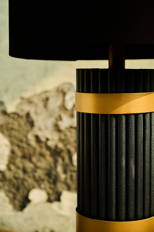 Black and gold lamp with textured design against a blurred natural background