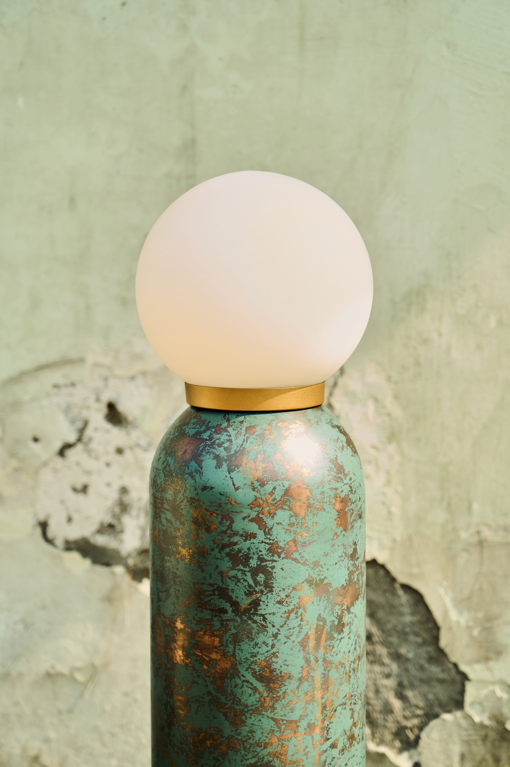 Decorative bottle with a textured green surface and a white spherical cap on a textured beige background