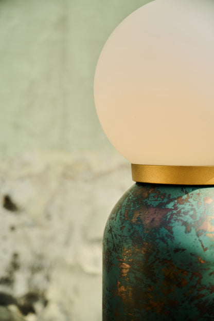 Close-up of a textured green bottle with a white cap on a blurred natural background