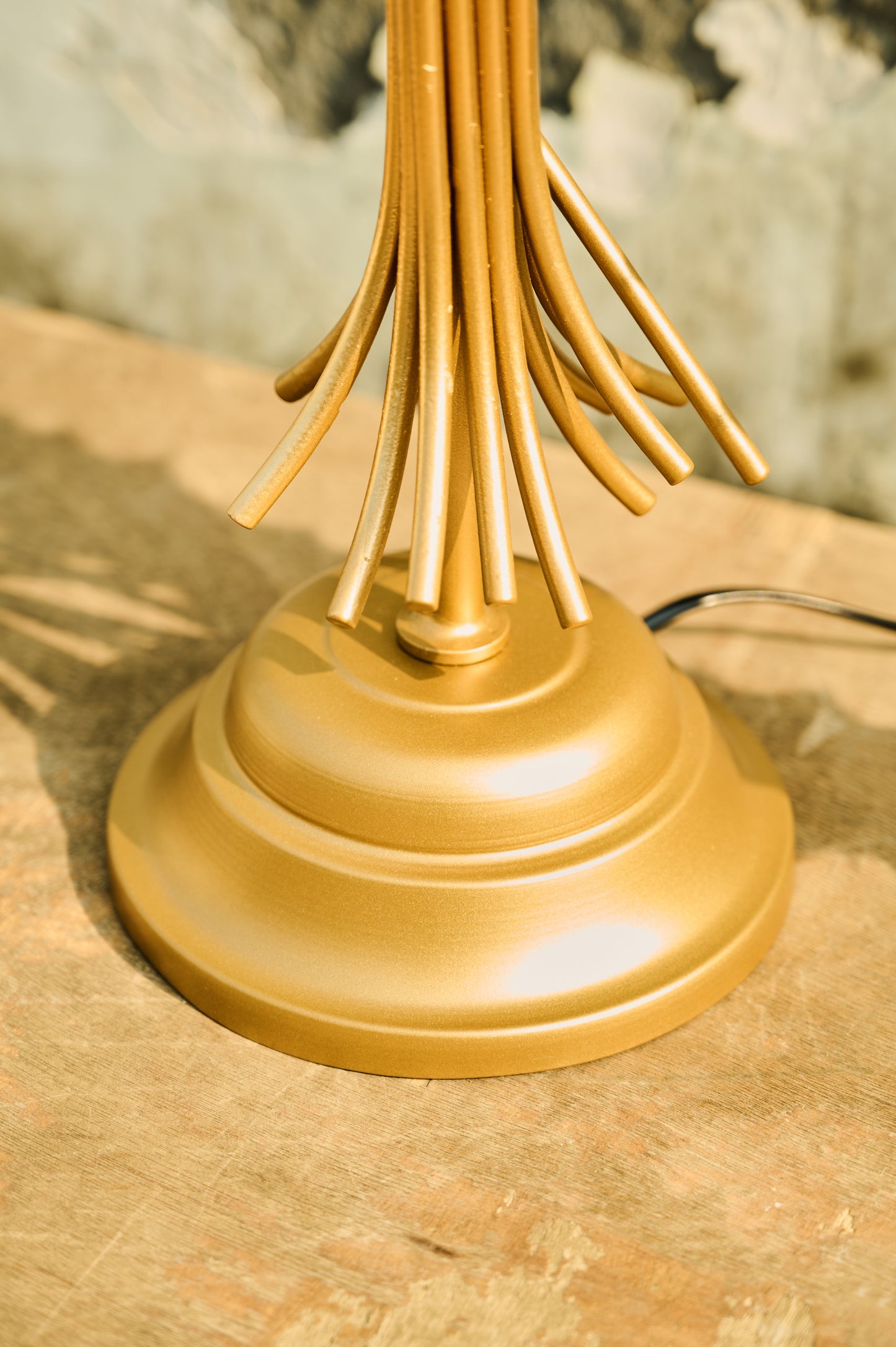 Gold lamp base on a wooden surface with a blurred background