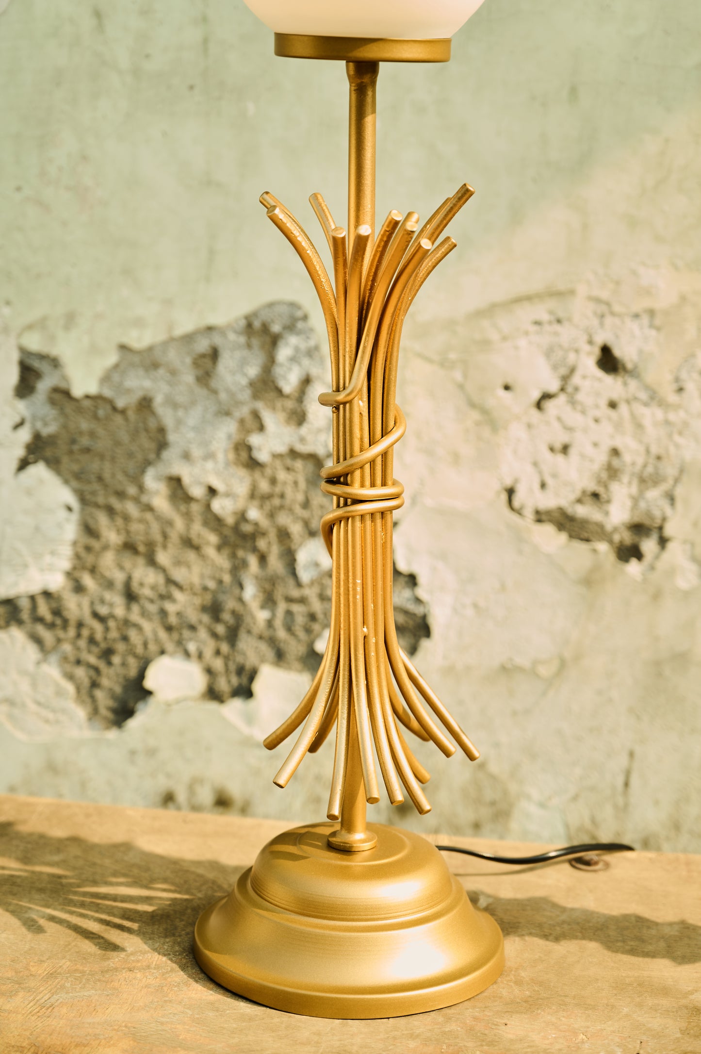 Gold lamp with branch-like design on a textured surface