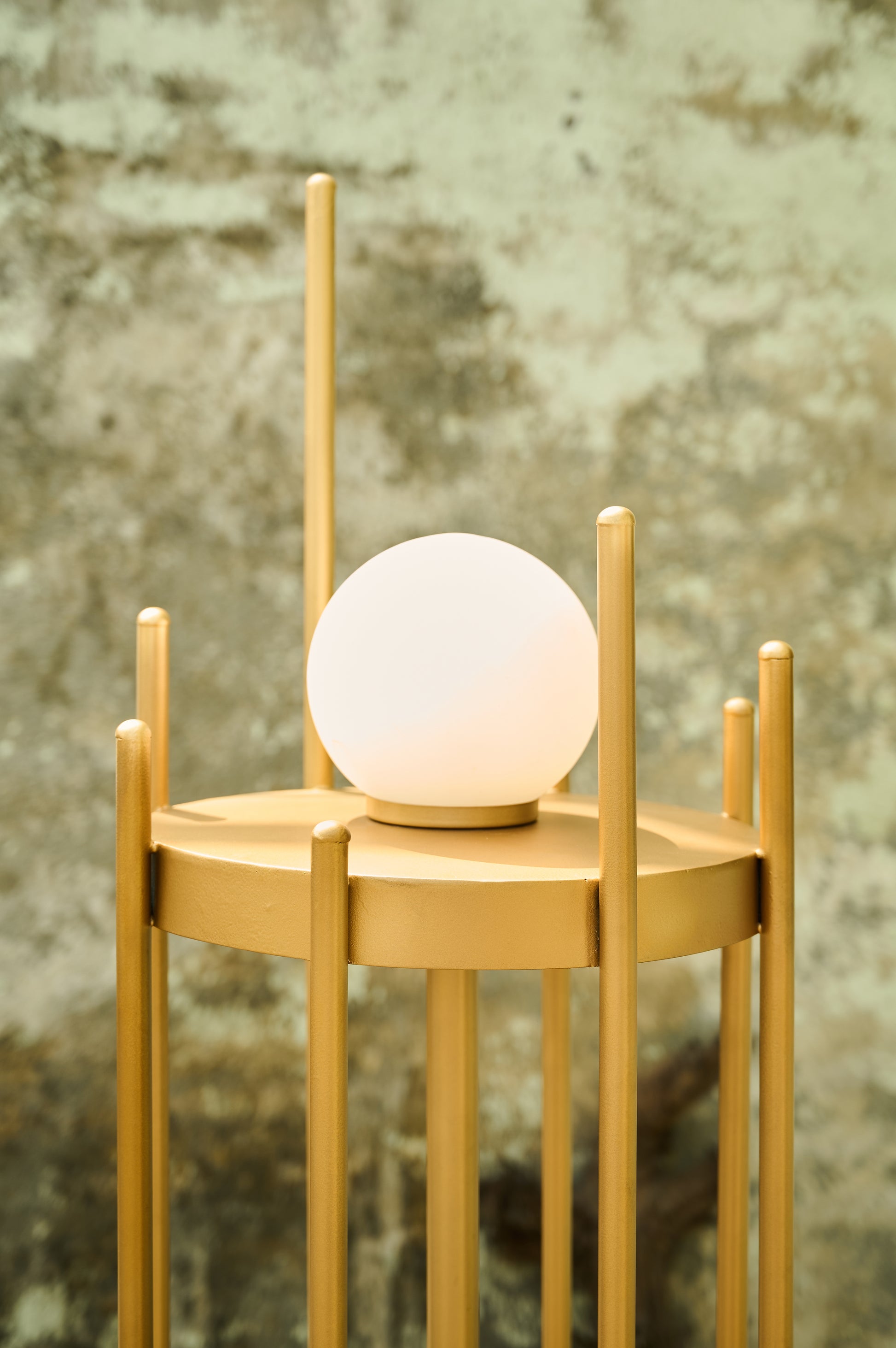 Small round table with a glowing light fixture against a textured wall.