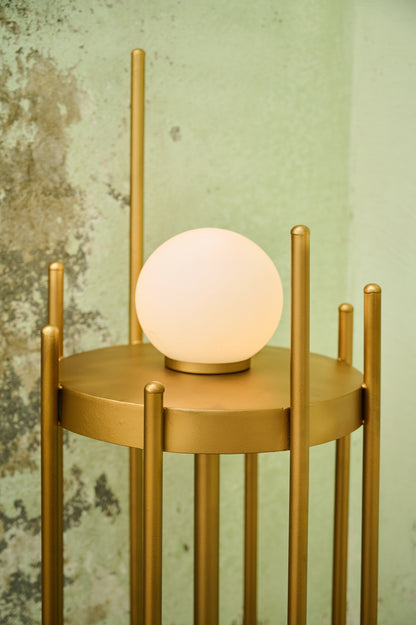 Gold side table with a round, glowing lamp against a textured wall.